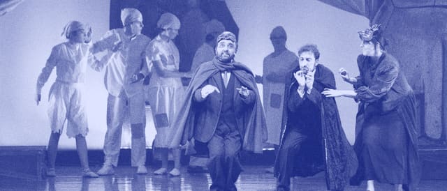 Performers from the academy on stage, one wearing a red cloak
