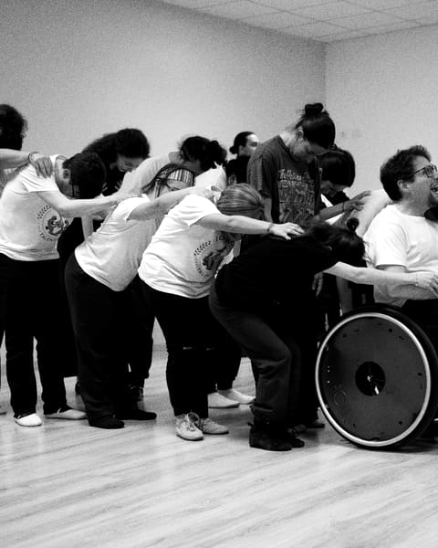 Students hugging in the rehearsal room, among them a young man in a wheelchair